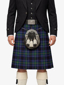 Person wearing a traditional Scottish kilt with a jacket and white shoes on a white background